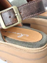 Zuecos de cuero color verde seco, con hebilla lateral y suela de goma.