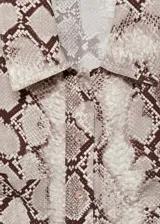 Vestido midi de corte recto con cuello camisero y cierre frontal de botones. Confeccionado en tejido fluido con estampado de serpiente, presenta mangas largas con puños abotonados, bolsillos de parche y trabillas para cinturón.