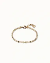 Pulsera de cadena compuesta por pequeños eslabones ovalados de acabado brillante, con cierre de mosquetón y dije colgante pequeño.