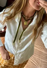 Colgante de estilo choker compuesto por una cinta de terciopelo verde con un dije de corazón en bronce y una cadena de cuentas de piedra natural en tonos verdes y rosados.