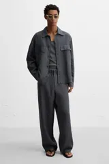 Sandalia minimalista de cuero negro, con tira delgada en el empeine y suela plana.