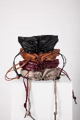 Bolso tipo sobre color bordó con diseño fruncido inspirado en la forma de un dumpling, con cierre ajustable mediante cordones y correa larga desmontable.