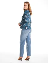 Blusa de seda fría con estampado floral en tonos verdes y azules. Presenta escote en V con un aplique metálico decorativo, mangas largas con puños y corte recto.