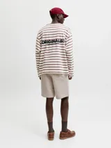 Bermuda deportiva beige de calce relajado, con costuras frontales en relieve y pequeño estampado lateral.