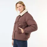 Campera acolchada corta color marrón con cuello de borreguito color crema. Presenta cierre frontal con botones a presión y bolsillos con solapa en el pecho.