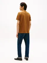 Remera de manga corta Tommy Hilfiger color marrón, con cuello redondo y una franja horizontal blanca en el pecho que incluye el logo de la marca estampado.