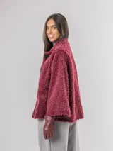 Chaqueta tipo capa de textura peluda en color bordó, con cuello mao y cierre frontal con botones grandes.