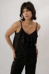 Musculosa negra con escote en V, breteles finos regulables y doble volado frontal con pespuntes.