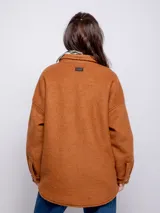 Sobrecamisa color beige de paño con cuello camisero, cierre frontal con botones veteados, dos bolsillos con solapa en el pecho y dos bolsillos laterales.