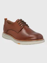 Zapato de vestir Hush Puppies modelo Rustic, confeccionado en cuero color marrón con cordones al tono. Presenta una suela de EVA en color gris claro con detalle de marca FLX en el lateral.