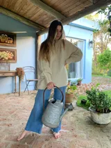 Sweater amplio de lana merino tejido a mano, color beige, con cuello redondo y mangas largas con diseño de trenzas.
