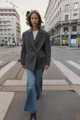 Blazer de corte oversize en color gris jaspeado, con cuello solapa, hombreras y cierre frontal cruzado con botones. Cuenta con bolsillos delanteros con solapa.