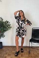 Camisa de manga larga con cuello y botones frontales, con un estampado abstracto en blanco, negro y rosado pálido. El corte es holgado y llega hasta medio muslo.