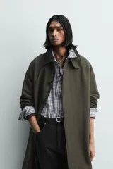 Trench de corte relajado confeccionado en tejido compacto de algodón. Presenta cuello solapa en color contraste, cierre frontal con botonadura oculta, bolsillos de vivo en la cadera y cintura ajustable con cinturón del mismo tejido. Las mangas largas cuentan con puños con trabilla y el bajo es ajustable en el centro de la espalda.