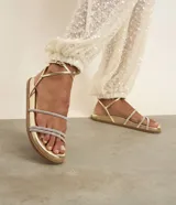 Sandalia plana Satinato de estilo sport, color dorado metalizado, con suela cómoda, tiras finas con aplicación de brillo y cierre de hebilla en el tobillo.