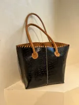 Bolso shopper de cuero azul con textura crocco, manijas largas marrones y costuras artesanales visibles en los bordes.