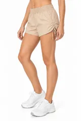 Short de poliamida color beige, holgado, de tiro medio con cintura elástica y detalles de frunces con cordones ajustables en los laterales.