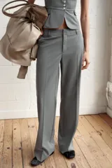Pantalón de vestir de tiro bajo con diseño de raya diplomática. Presenta corte recto, trabillas para cinturón, bolsillos laterales y cierre frontal con cremallera, botón y ganchos metálicos.