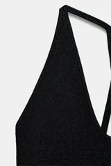 Top corto negro con textura brillante, escote pronunciado en V y tirantes finos que se cruzan en la espalda en diseño tipo nadador.