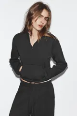 Sudadera de algodón con cuello subido y cierre frontal con cremallera. Presenta mangas largas, bolsillo tipo canguro frontal y bajo ajustable con cordones.