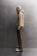 Chaqueta de hombre color marrón óxido con textura de pequeños cuadrados en relieve. Presenta cierre frontal de cremallera, capucha ajustable, bolsillos laterales con solapa y puños ajustables. El interior es de forro polar.