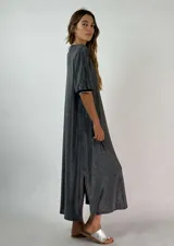 Vestido midi dorado con brillo, escote en V con ribete blanco y mangas cortas con puños blancos. Tiene aberturas laterales en el ruedo.