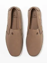 Mocasín negro de cuero sintético, con elástico en los laterales y suela de goma.