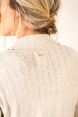 Cardigan color salmón de algodón y elastano, con solapa y lazo ajustable en la cintura.