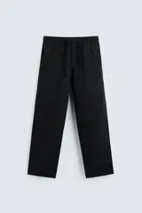 Pantalón negro de corte relajado (relaxed fit) con cintura elástica ajustable mediante cordón. Presenta bolsillos frontales y bolsillos traseros de vivo.