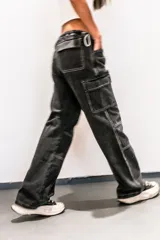 Pantalón jean negro de corte parachute, tiro bajo, pierna ancha y bolsillos cargo.