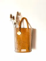 Bolso matero de cuero color marrón con textura croco y detalles en cuero color taupe. Tiene doble asa corta de cuero y un dije colgante en forma de cruz.