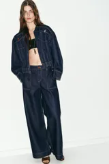 Jeans de tiro medio con corte wide leg y pernera ancha. Presenta bolsillos de plastrón en el delantero y cierre frontal con cremallera y botón.