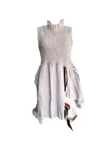 Vestido corto sin mangas de lino natural color beige, con corpiño fruncido, cuello alto con volante y falda de caída irregular con aplicaciones de cuero y pelo.