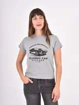 Remera gris de corte clásico con cuello redondo y mangas cortas. Presenta un estampado frontal en color negro con la ilustración de un auto clásico y la leyenda 'Superior Performance Classic Car Garage Estd 1980'.