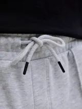 Bermuda deportiva gris melange de felpa, con calce relajado, tiro bajo, bolsillos laterales y pequeño estampado con texto en la pierna izquierda.