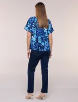 Blusa de poliéster azul con estampado botánico y floral, de silueta holgada y fluido diseño. Cuenta con escote redondo elastizado con frunces y mangas cortas amplias.