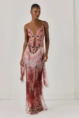Vestido largo ajustado de tul, con diseño de mariposa bordado en cuentas en el busto, abertura frontal, tirantes finos y falda con flecos de cuentas en degradado de tonos rojizos.