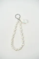 Llavero de muñeca con tira de cuentas en forma de perlas y conchas marinas, y un dije de caracola nacarada. Incluye argolla metálica circular.