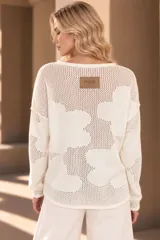 Buzo de tejido de punto calado color celeste, con diseño de flores, escote redondo y mangas largas.