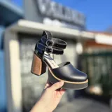 Zapatos de tacón alto Perla con plataforma, diseño de doble tira con hebillas en el tobillo, taco ancho de madera y capellada negra.