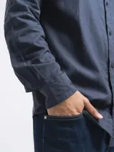 Camisa de manga larga, color blanco, con cuello camisero y botones frontales. El tejido presenta una textura visible de lino.