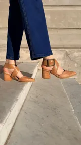 Zapatos de tacón ancho color camel con textura símil serpiente, punta fina y tiras cruzadas con hebilla metálica grande en el lateral.