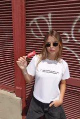 Remera blanca de algodón con cuello redondo y manga corta, con texto estampado en negro en el pecho que dice "If I am flirting with you, please cooperate".