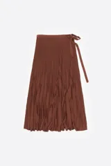 Falda midi plisada de color marrón, con diseño cruzado (wrap) y lazada de ajuste lateral en la cintura.