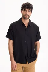 Camisa de manga corta negra, de corte clásico y cuello camisero.
