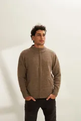 Campera tejida color marrón claro con cierre delantero, cuello alto y bolsillos delanteros. Tejida en 100% lana fina sin teñir.