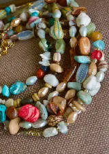 Gargantilla corta de piedras naturales multicolor, con cuentas de diferentes formas, tamaños y tonos como turquesa, marrón, blanco, rojo y celeste.
