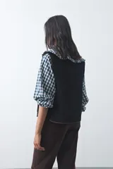 Chaleco de pana negro con diseño capitoneado, cierre frontal de botones y bolsillos de parche con terminaciones en contraste. Presenta un calce relajado y estructura acolchada.