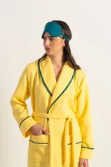 Bata clásica amarilla con textura capitoné y ribete verde en cuello, solapa, puños y cinturón.