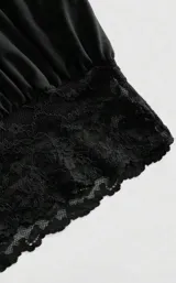 Top negro con escote halter cruzado y detalle de puntilla en el borde inferior.